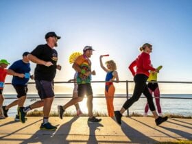 Runners and course entertainers as the sunrises in the background over Queens Beach