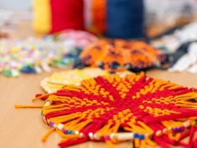 Small, orange and red woven wagon wheel on table.