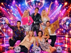 A group of seven people in glittery, discoâinspired outfits posing under mirror ball