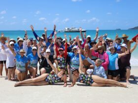 group photo on Whitehaven beach post swimming event with hands in the air celebrating