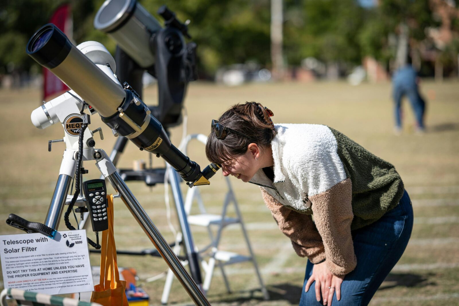 A lady looks through a solar telescope in broad daylight