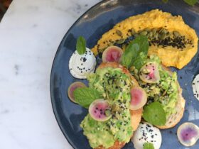 Avocado on sourdough toast with a generous smear of pumpkin hummus and dollops of whips goats curd.