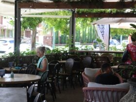 Veranda covered in tables to dine at with a passionfruit vine around the railings.