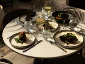 Flat lay of different dishes on a table with shadows, with glasses of water and wine.