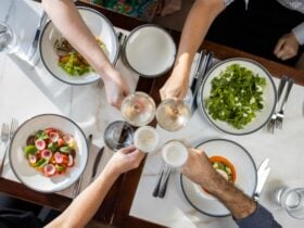 Group dining with hands in doing a cheers over lunch