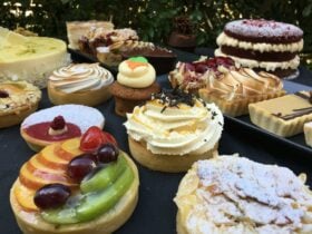 A selection of pastries and cakes sitting on a table in front of a hedge