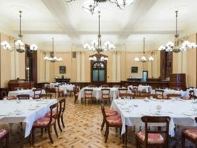 Formal dining room with set tables, lighting, and wooden floors.