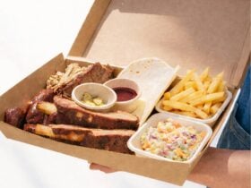 Smoked BBQ share platter with brisket, beef ribs, pulled pork, fries, coleslaw, pickles served a box