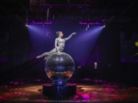 Giant Mirror Ball with performer on top posing with her arm out