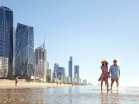 A couple strolling along the beach near a high-rise city skyline