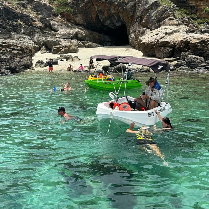 Snorkelling beside hire boats in clear water at Great Keppel Island, QLD.