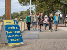 A guide talking while visitors are walking alongside him, near the Redcliffe Jetty.