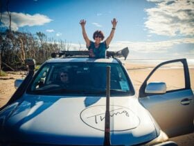 Customer posing through a sunroof in a 4WD on the beach