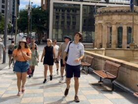 A tour group walks along a patterned stone pathway in a city center.