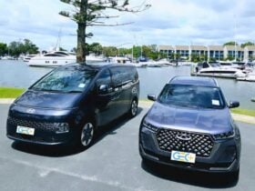 Hyundai van and Chery SUV from GEC Transfers parked near a marina with yachts and waterfront
