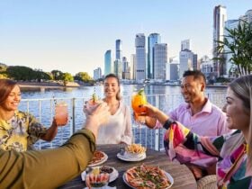 A group of friends alfresco dining and cheering over cocktails at riverside bar brisbane city