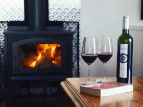 Two glasses of red wine in front of a raging fire
