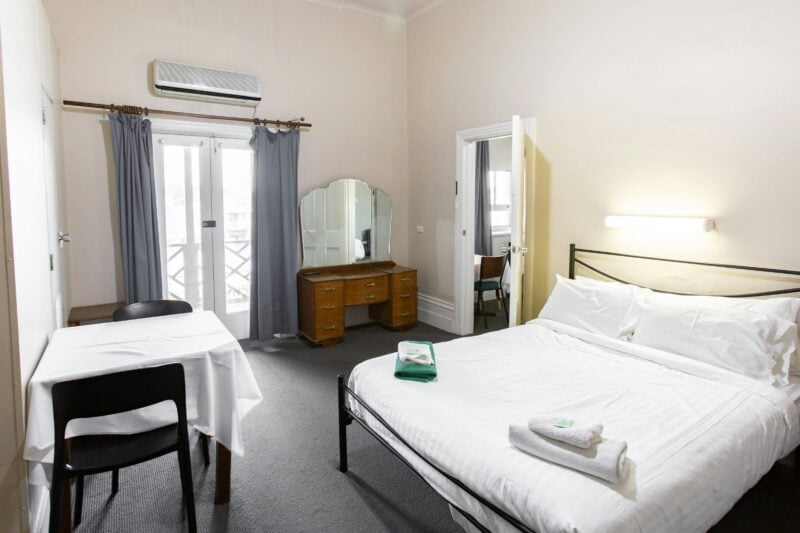Interior of a double room with a queen-sized bed, dressing table, and balcony access.