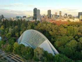 A drone photo showing a glass conservatory and city in the background