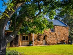 Converted stone stable with tree and lawn in foreground
