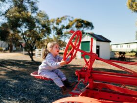 small child riding a stationary red tractor at Pioneer Park