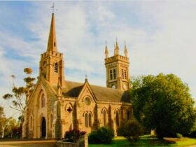 Photo of St Andrews front entrance and spire, with clock tower behind.