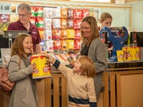 A family at the candy bar has made their purchase. A young boy and takes popcorn from his sister