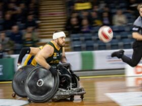 An athlete with a head bandage chases the ball down the court.