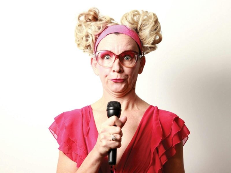 Comedian Kiki Bitovabitsch with a microphone and an animated face