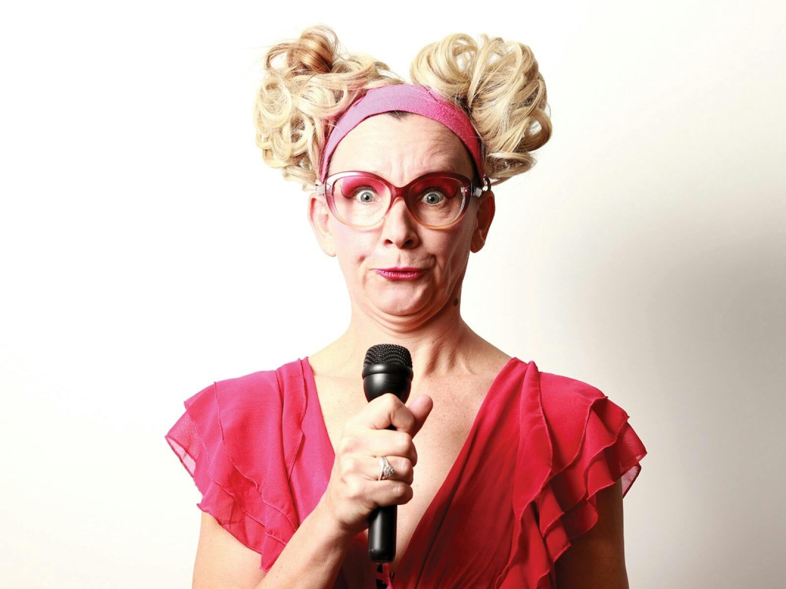 Women looking at the camera, holding a microphone with a funny expression on her face.