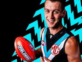Man holding red football standing in front of a black background