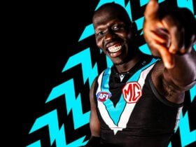 Man standing in front of black and teal arrows pointing towards the camera