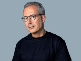 A man in a black tshirt and blue glasses