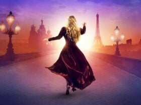 A blonde woman in a velvet dress stands with her back to the viewer reaching toward a sunrise