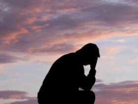 Silhoutte of a man kneeling down on one knee with his head in his hand as a symbol of remembrance