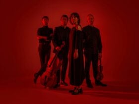 The Quartet stand wearing all black on a red backdrop. L to R is Chris, Michael, Fran and Dale