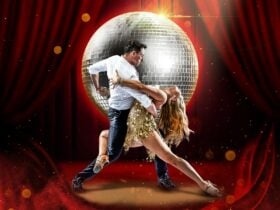 A man and a woman perform a dramatic dip in front of a glowing disco ball