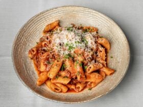 A bowl of penne beef cheek ragu topped with parmesan
