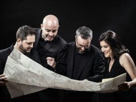 The members of Cuarteto Quiroga surveying a map against a black background.