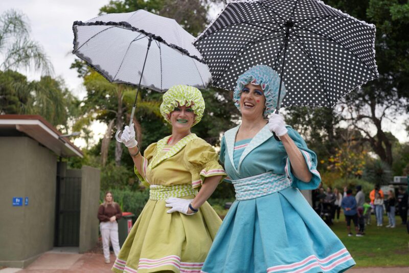 Two Slack Taxi stilt walkers dressed in vintage costume in the Ada Ryan Gardens