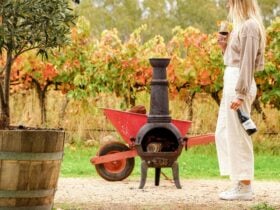 A young lady samples wine by a crackling fire in an autumn vineyard