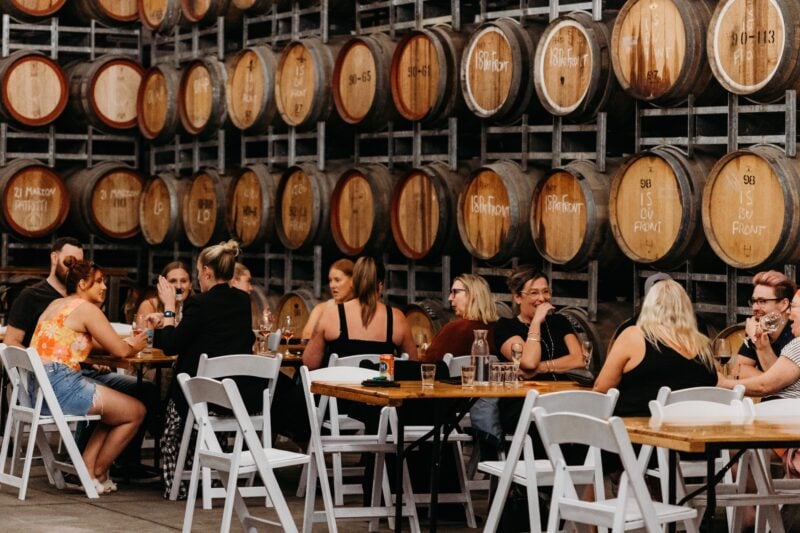 People drinking wine in barrel warehouse
