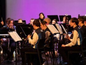 A concert band dressed in blue and white performing on a stage