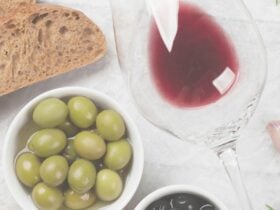 Olives, bread and red wine in a glass on a white table