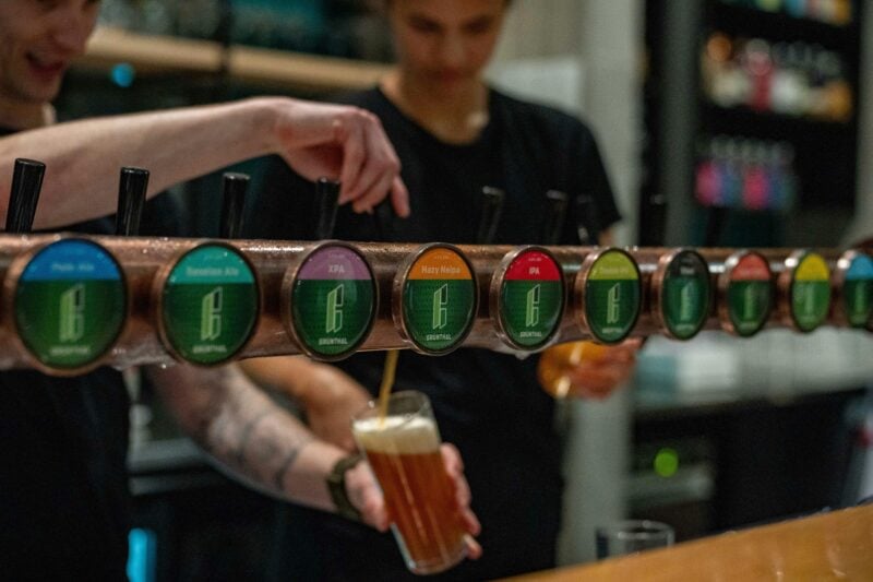 Bar tender pouring beer off tap into pint glass