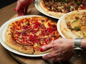 hands placing a pizza on table