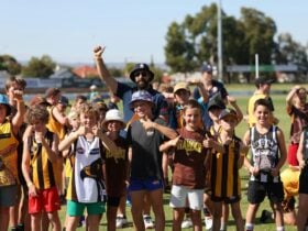 Children smiling to camera giving a thumbs up