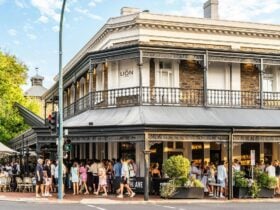 A heritage pub viewed from across the street; its awning and verandah are packed out with patrons.