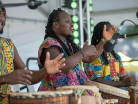 Three African drummers wearing colourful outfits perform on stage at Marion Celebrates.