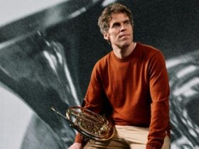 A horn player holding their instrument and smiling